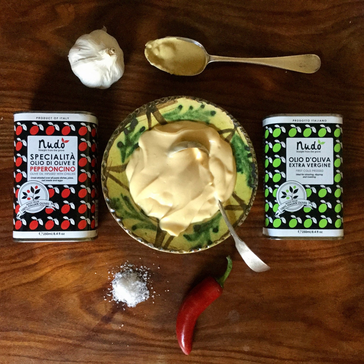 Flatlay-image-of-two-tins-of-olive-oil-with a bowl-of-maynaise,-spoon-of-mustard,-garlic-bulb-pile-of-salt-and-red-chilli
