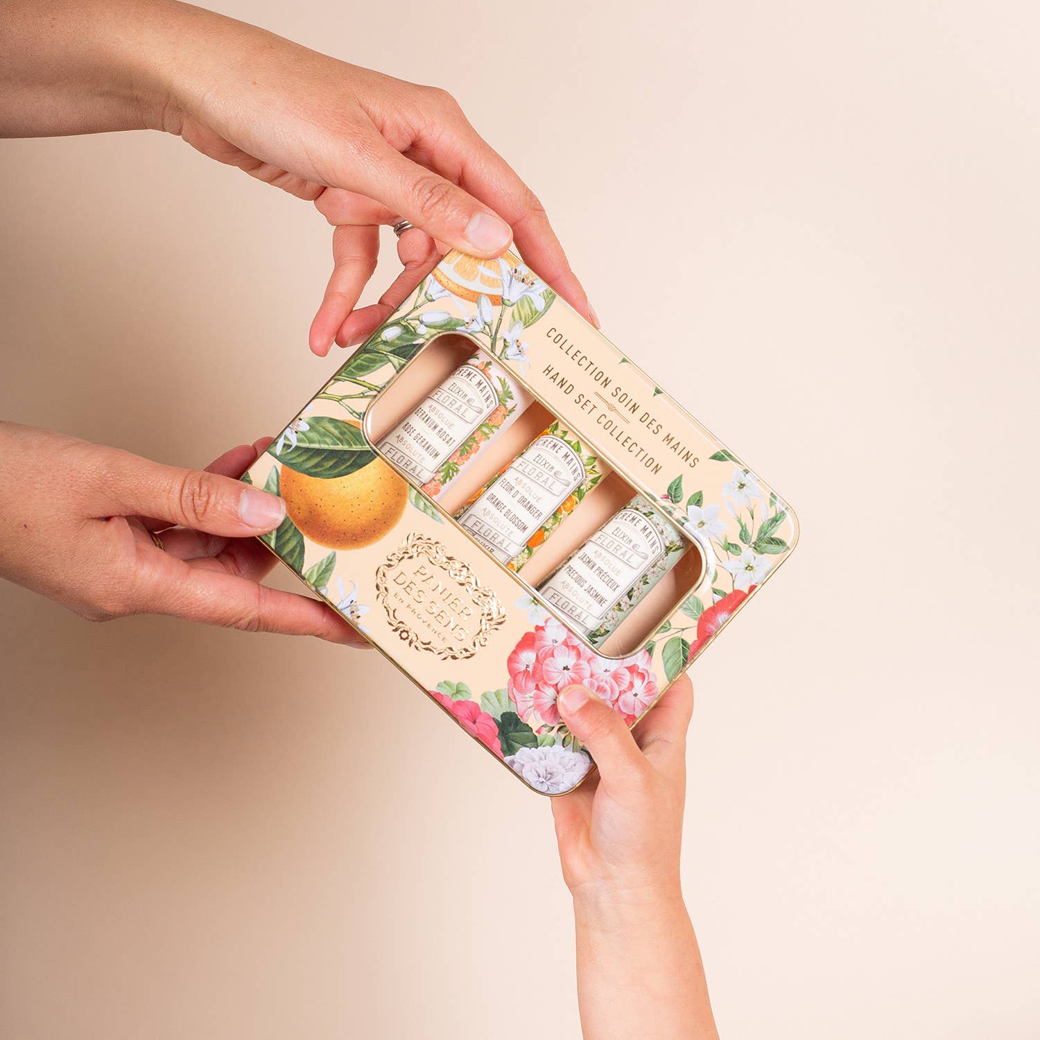 Floral-themed makeup set held by hands against a beige background