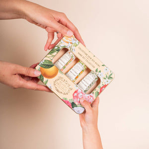 Floral-themed makeup set held by hands against a beige background