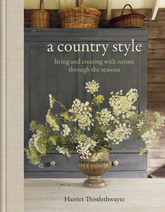 Book cover of 'A Country Style' by Harriet Thistlethwayte with a decorative cabinet and floral arrangement.