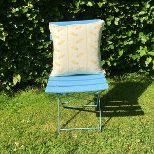 Yellow Cushion on blue chair on lawn