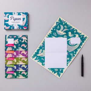 Note letter  with bird pattern, colorful packaging, and pen on gray background