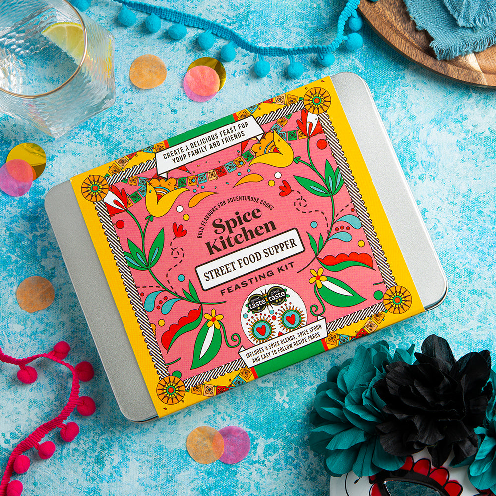 Spice Kitchen Street Food Supper kit on a colorful background with flowers and a glass of water.
