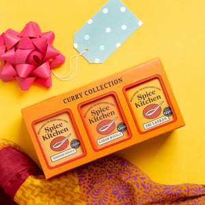 Spice Kitchen Curry Collection packaging on a yellow background with a pink bow and gift tag.