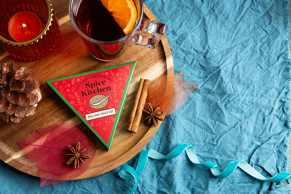 Spice package on a wooden tray with a glass of tea and decorative elements on a blue fabric background