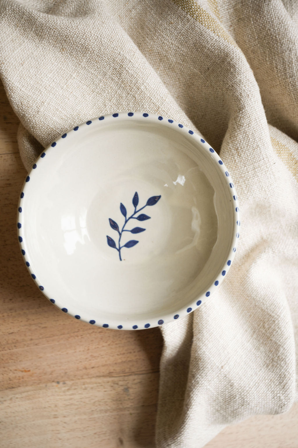 pottery-bowl-with-blue-dot-rim-sprig-inside-on-wooden-top-with -linen-cloth